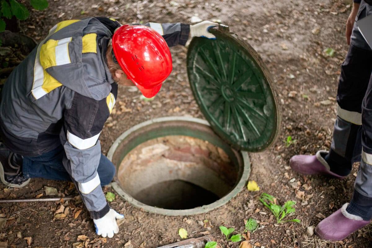 Workers inspecting an open underground wastewater access point